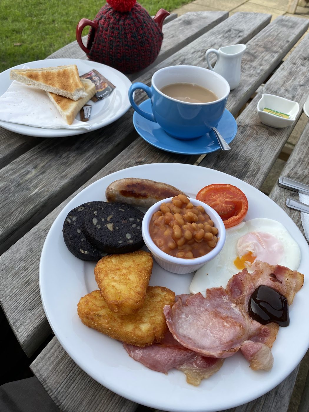 A cooked breakfast with black pudding, bacon, beans and hash browns