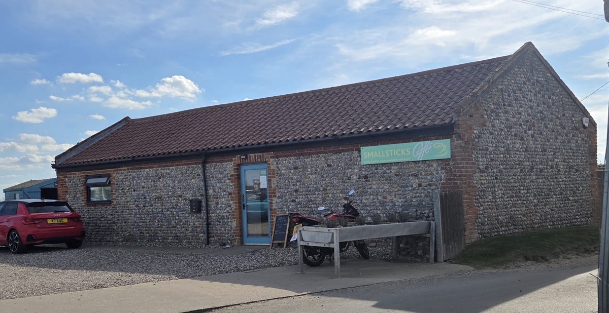 The flint and brick building with a blue door and the green SMALLSTICKS Café sign